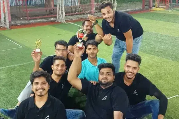 Teammates holding up trophies on a football turf